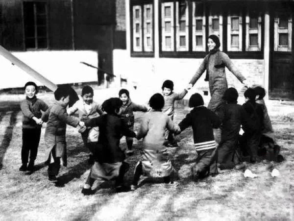 1935年，南京金陵女子文理学院的一位幼儿园女教师带着孩子在草坪上做游戏。.jpeg