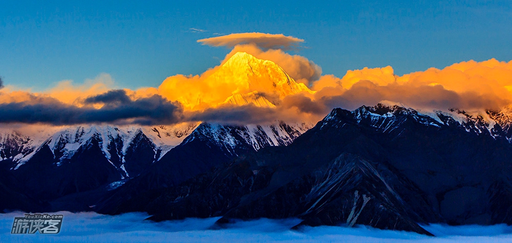 夕阳照亮贡嘎雪山上的蘑菇云，呈现梦幻的场景。