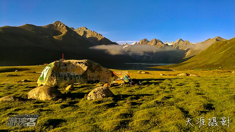 柔和的阳光撒在雪山、湖水、草地和各色的小花上，呈现世外桃源般的唯美景象。